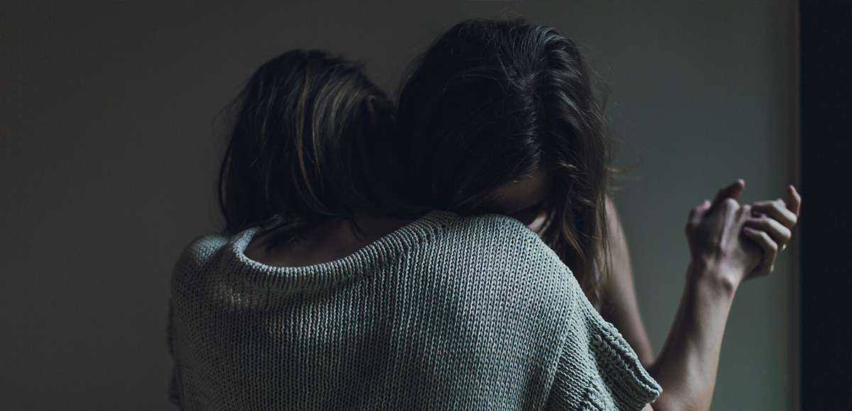 Dwie płaczące kobiety wtulone w w swoje ramiona
