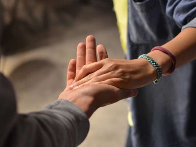 Osoba chwyta drugą osobę za dłoń w geście wsparcia.